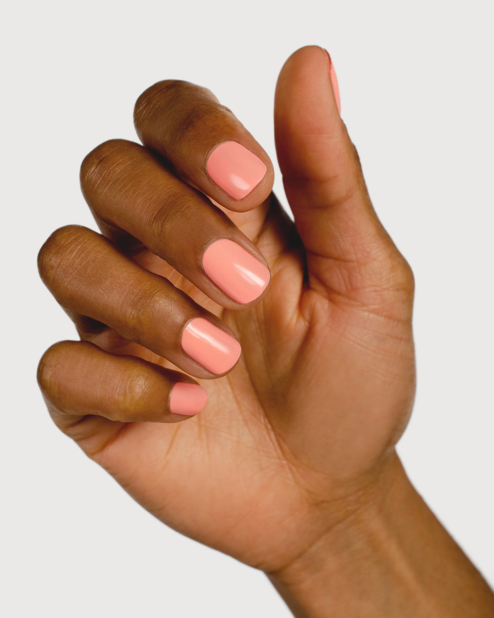 Vibrant peach nail polish hand swatch on medium skin tone